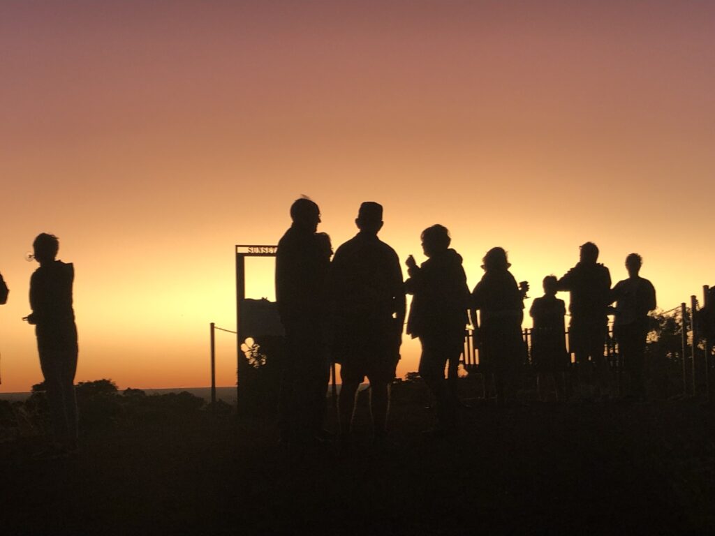 People drinking champagne at the top of Mt Walker with the sunrise in the background.